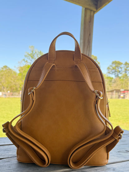 Mustard leather backpack on a wooden surface with a blurred outdoor background