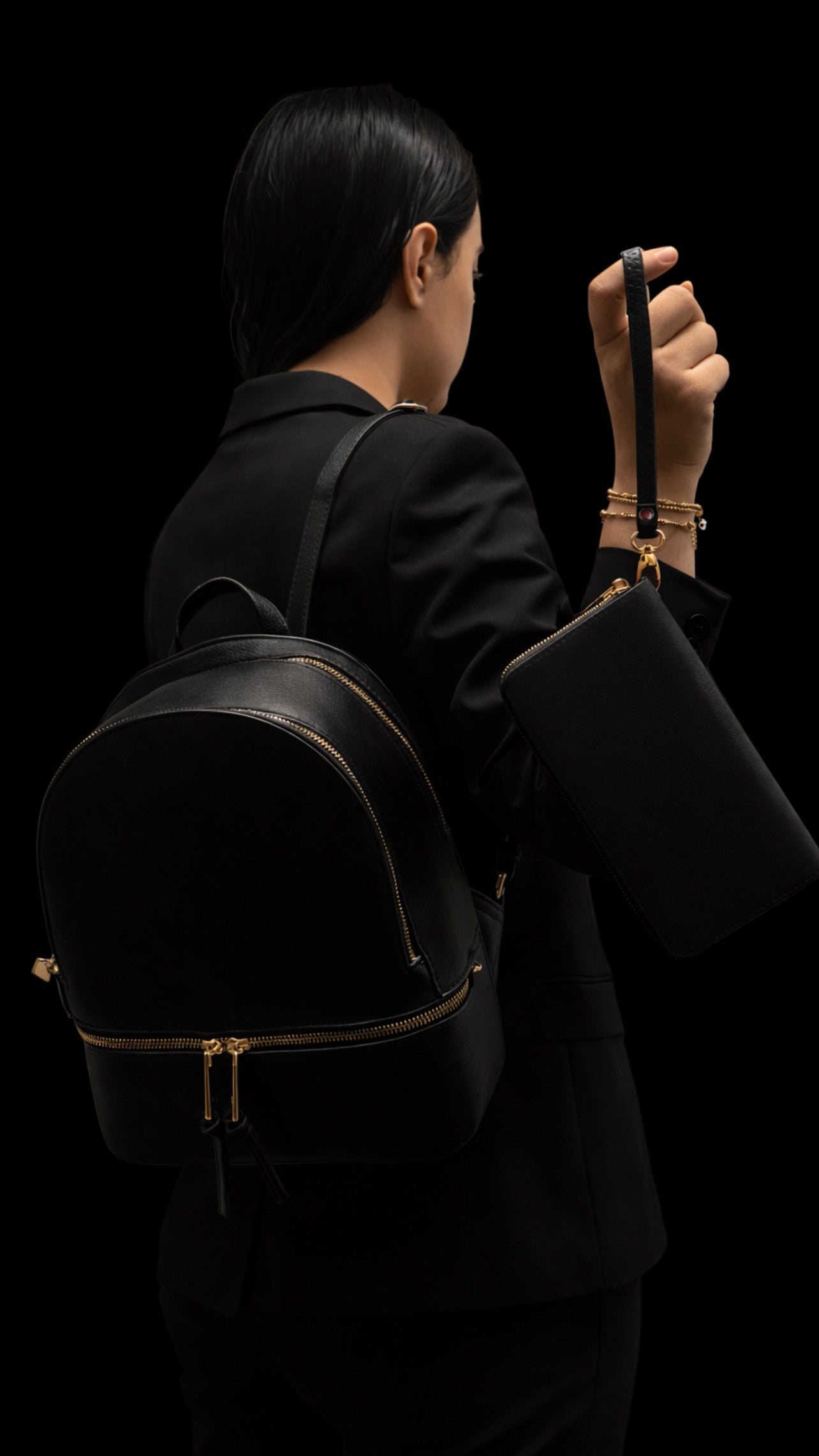 Person wearing a black backpack against a black background